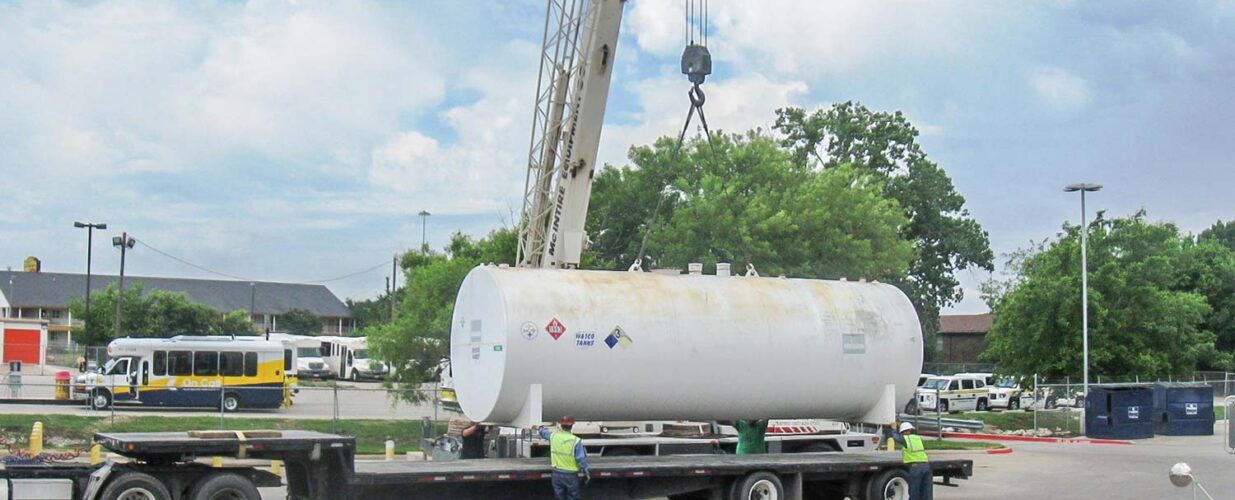 workers next to crane lifting tank for DART environmental project